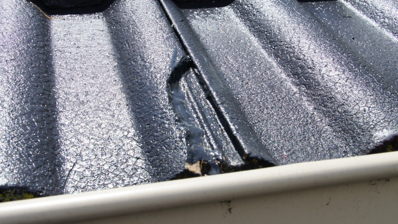 Broken grey tile on a cement roof needing replacement