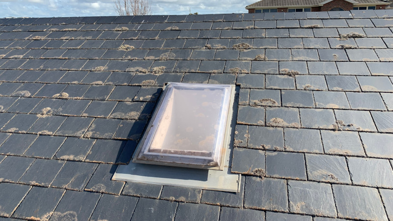 Broken grey tile on a cement roof needing replacement